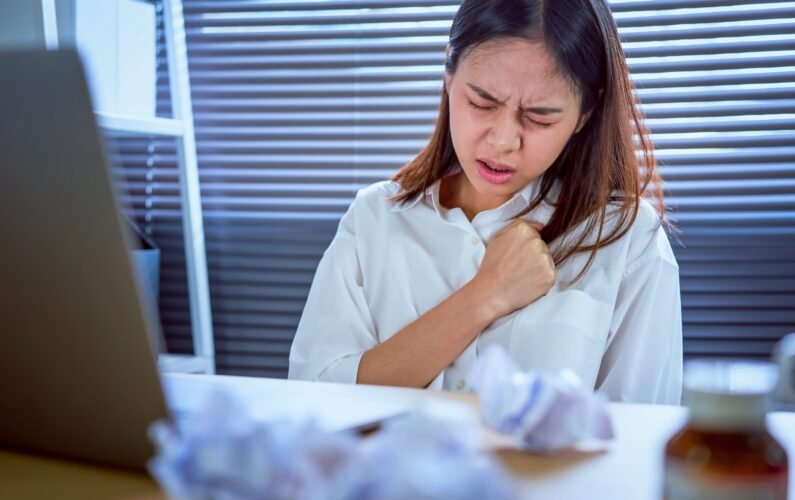 Asian business woman hand pressing on chest with painful expression. Symptoms of heart disease because working too hard.