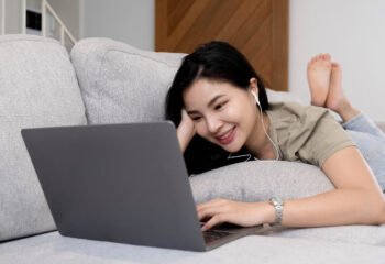 social media time stay in touch with her tablet A cheerful woman lies on the sofa using a tablet at home in the living room. smiling woman with tablet on sofa.