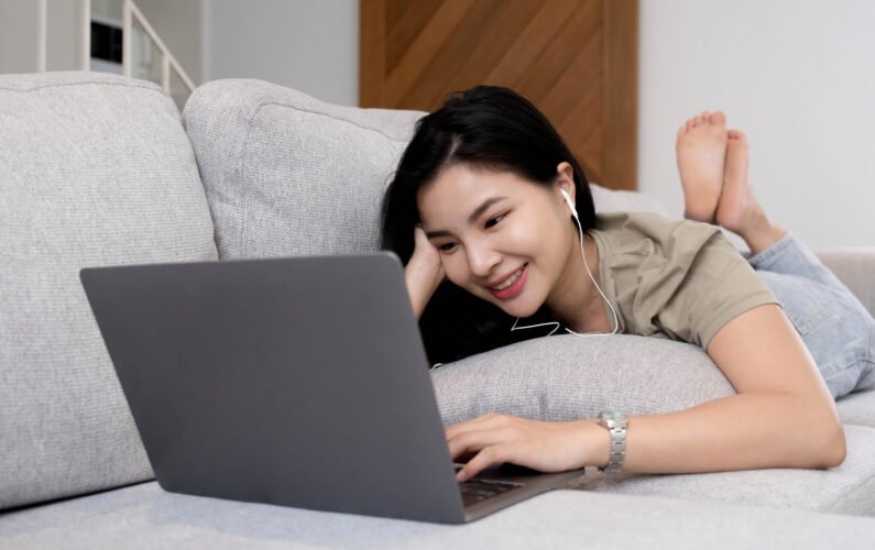 social media time stay in touch with her tablet A cheerful woman lies on the sofa using a tablet at home in the living room. smiling woman with tablet on sofa.