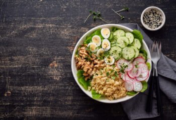 Buddha bowl, balanced food, vegetarian menu, dash diet. Dark wooden table. Eggs lettuce bulgur radish cucumber walnut. Copy space