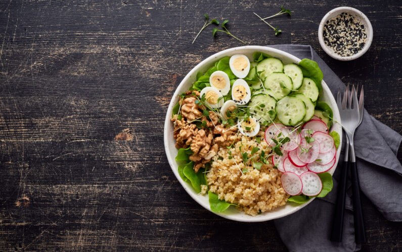 Buddha bowl, balanced food, vegetarian menu, dash diet. Dark wooden table. Eggs lettuce bulgur radish cucumber walnut. Copy space